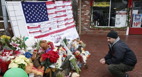A mourner pays his respects near a US flag showing the names of victims at a makeshift memorial in the Sandy Hook village of Newtown. Picture: AP